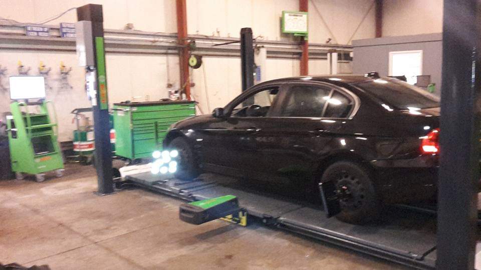 Zwarte auto op het 3D-uitlijnplatform in de werkplaats